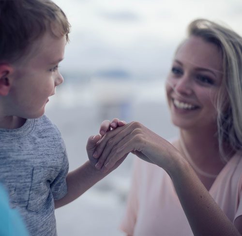 A mother holding her toddler son's hand.