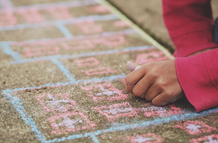 Children drawing on a sidewalk with chalk.