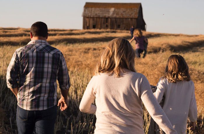 A family walking through a hay field.